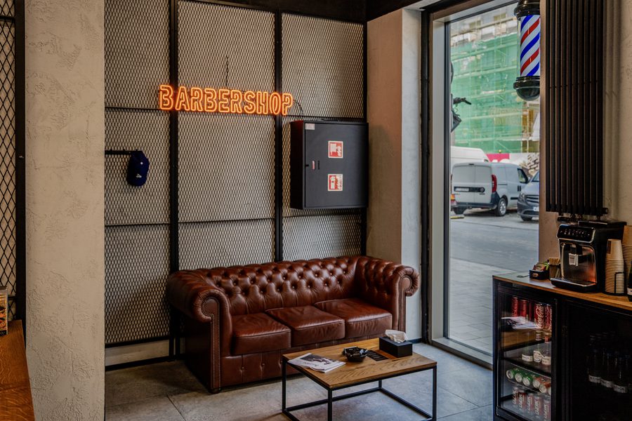 Barbers Lab - strefa oczekiwania ze skórzaną sofą i neonem BARBERSHOP
